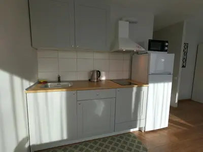 a kitchen with white cabinets and a sink and a refrigerator at Stay in center #Šiauliai in Šiauliai