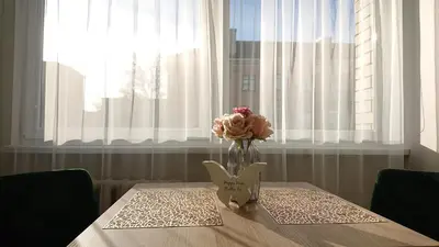 a vase of flowers on a table with a window at Stay in center #Šiauliai in Šiauliai