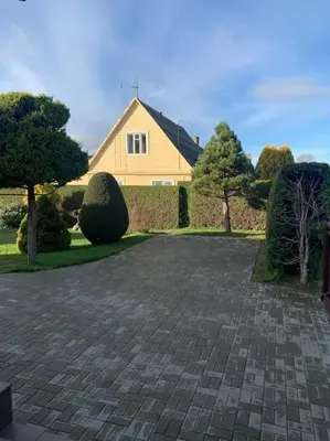a brick driveway in front of a yellow house at Cozy apartment in Karmelava in Karmėlava