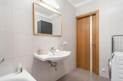 a white bathroom with a sink and a mirror at Business Apartment In Jaksto Street in Vilnius