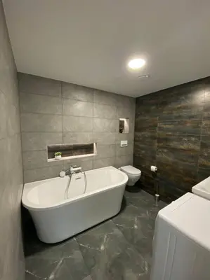 a bathroom with a white tub and a toilet at Ukmergė Apartments in Ukmergė