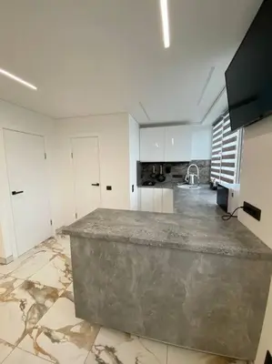 a large kitchen with white cabinets and a large island at Ukmergė Apartments in Ukmergė