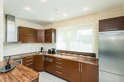 a kitchen with wooden cabinets and a stainless steel refrigerator at 3-bedroom villa surrounded by beautiful nature in Vaišvydava