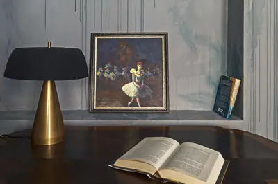 an open book on a desk with a lamp and a painting at Luxuriuos flat in the capital's old town in Vilnius