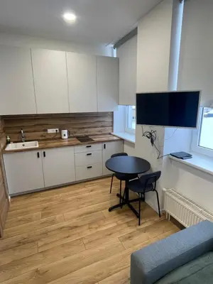 a kitchen with white cabinets and a table and a sink at 32 Airport Apartment in Vilnius