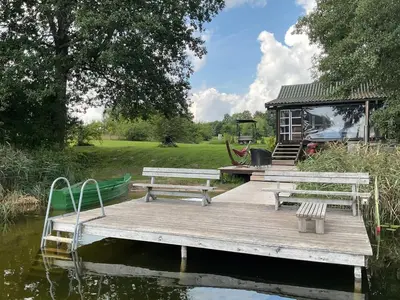 a dock with benches and a house on the water at Pirtelė Arjola in Kaltanėnai