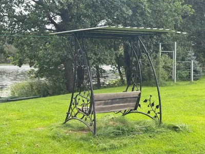 a park bench with a canopy in the grass at Pirtelė Arjola in Kaltanėnai