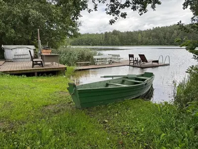 a green boat sitting on the grass next to a dock at Pirtelė Arjola in Kaltanėnai