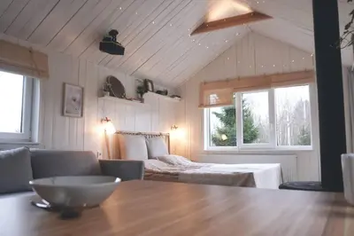 a room with a table and a bed and windows at Hand made Off Grid forest Cabin Luna in Luksine