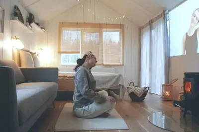 a woman sitting on the floor in a living room at Hand made Off Grid forest Cabin Luna in Luksine