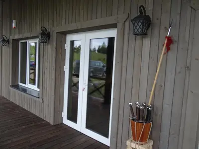 a porch of a cabin with a door and utensils at Sodyba PILIAKIEMIS in Kurkliškės
