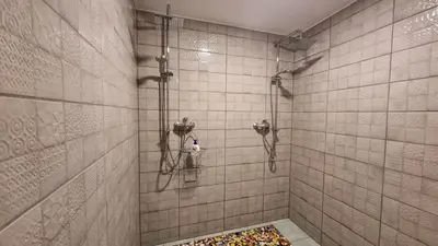 a bathroom with a shower with a colorful rug at Sodyba PILIAKIEMIS in Kurkliškės