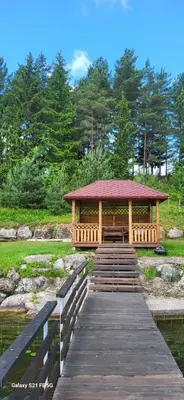a wooden boardwalk leading to a gazebo over a pond at Drulenu sodyba in Drūlėnai