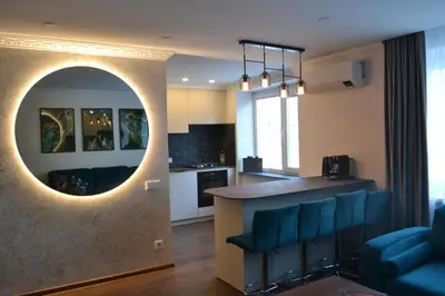 a kitchen and living room with a counter and blue chairs at E. D. Elite Apartment in Šiauliai