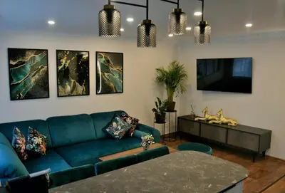 a living room with a blue couch and paintings on the wall at E. D. Elite Apartment in Šiauliai