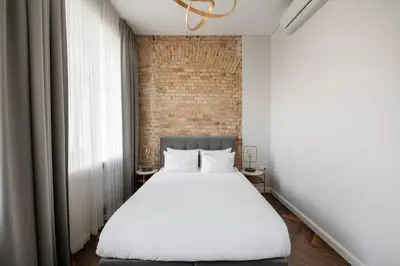a bedroom with a white bed and a brick wall at GRAND CROWN in Vilnius
