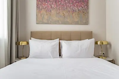 a bedroom with a bed with white pillows and a painting at GRAND CROWN in Vilnius