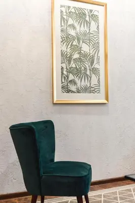 a green chair sitting next to a wall with a picture at Courtyard gallery apartment with free parking in Kaunas