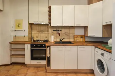 a kitchen with white cabinets and a sink and a dishwasher at Courtyard gallery apartment with free parking in Kaunas