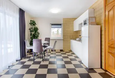 a kitchen and dining room with a table and a refrigerator at Namo-pirties nuoma Vinkšnėnuose in Vijoliai