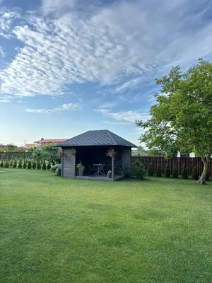 a small shed in a yard with a green lawn at Namo-pirties nuoma Vinkšnėnuose in Vijoliai