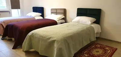 a room with three beds with blankets and a rug at EMVIKA apartament in Šiauliai