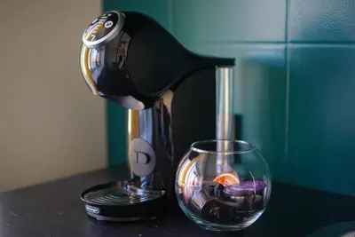 a coffee maker sitting on a counter next to a glass at Apartment Secret in Jonava