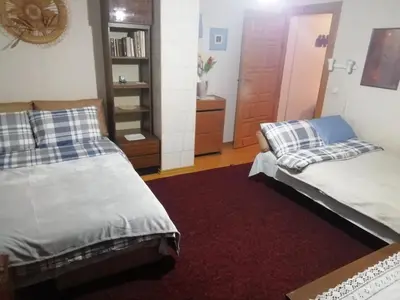 a bedroom with two beds and a book shelf at Poilsio kambariai Salake in Salakas