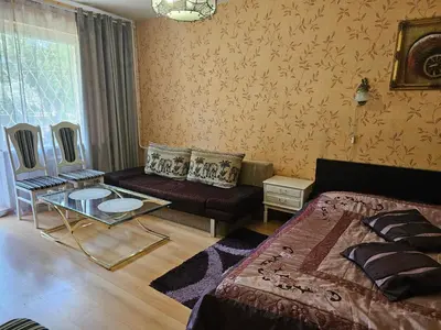 a bedroom with a bed and a couch and a table at Vieno kambario butas su balkonu in Kaunas