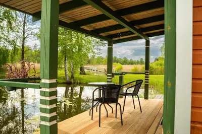 a wooden deck with a table and chairs on a lake at Namelis ant kranto - Alaušo Salos in Sudeikiai