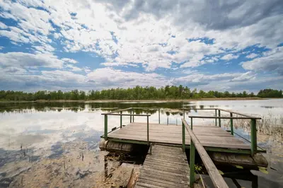 a wooden dock in the middle of a lake at Namelis ant kranto - Alaušo Salos in Sudeikiai