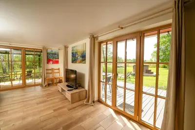 a living room with sliding glass doors and a television at Namelis ant kranto - Alaušo Salos in Sudeikiai