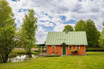 a small house with a green roof in a field at Namelis ant kranto - Alaušo Salos in Sudeikiai