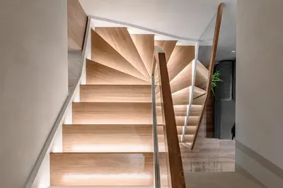 a spiral staircase with wood treads in a house at Miško Spa namas in Molėtai