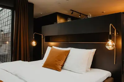 a bedroom with a bed with white pillows and lights at Atokampis Boutique SPA & Resort in Anglininkai