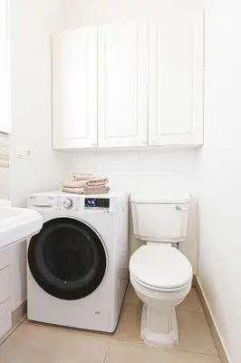 a white bathroom with a washing machine and a toilet at Central Stylish Well Equiped Apartments - Self Check-in in Vilnius