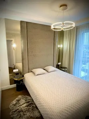 a bedroom with a large bed and a chandelier at New luxury apartment & free parking in Vilnius