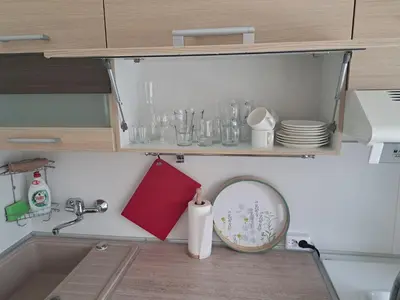 a kitchen counter with a sink and a shelf with dishes at Sweet home in Šiauliai