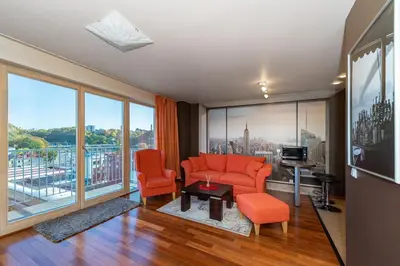 a living room with orange furniture and large windows at Panoramic city centre apartment by Polo Apartments in Kaunas