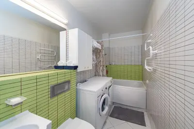 a bathroom with a washing machine and a green wall at Panoramic city centre apartment by Polo Apartments in Kaunas