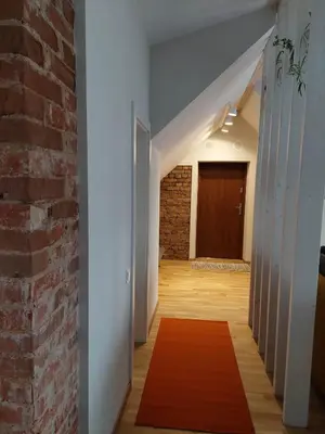 a hallway with a brick wall and a red rug at Maple Park Apartment in Kaunas