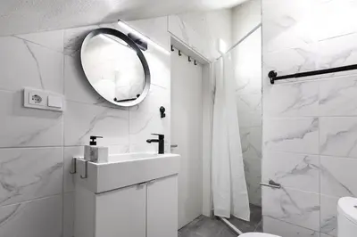 a white bathroom with a sink and a mirror at Luxury apartment in Gediminas avenue with terrace in Vilnius