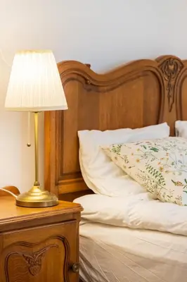 a lamp on a night stand next to a bed at Doma3 Luxury Vilnius Apartment in Vilnius