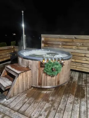 a hot tub sitting on a wooden deck at night at ODM&A apartment in Vilnius