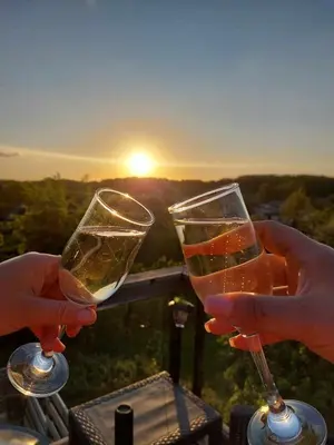 two people holding wine glasses with the sunset in the background at ODM&A apartment in Vilnius