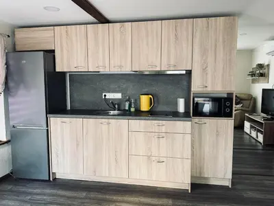 a kitchen with wooden cabinets and a stainless steel refrigerator at ODM&A apartment in Vilnius
