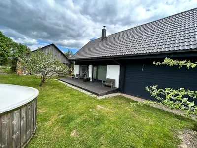 a blue house with a porch and a yard at Barn Guest House in Kazitiškis