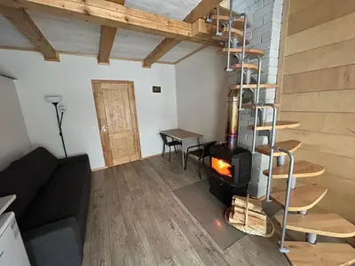 a living room with a fireplace and a staircase at Barn Guest House in Kazitiškis