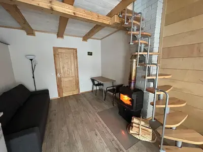 a living room with a fireplace and a spiral staircase at Barn Guest House in Kazitiškis