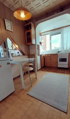 a kitchen with a white table and a kitchen with a window at Erdvus butas su balkonu šalia ežero ir stadiono in Visaginas